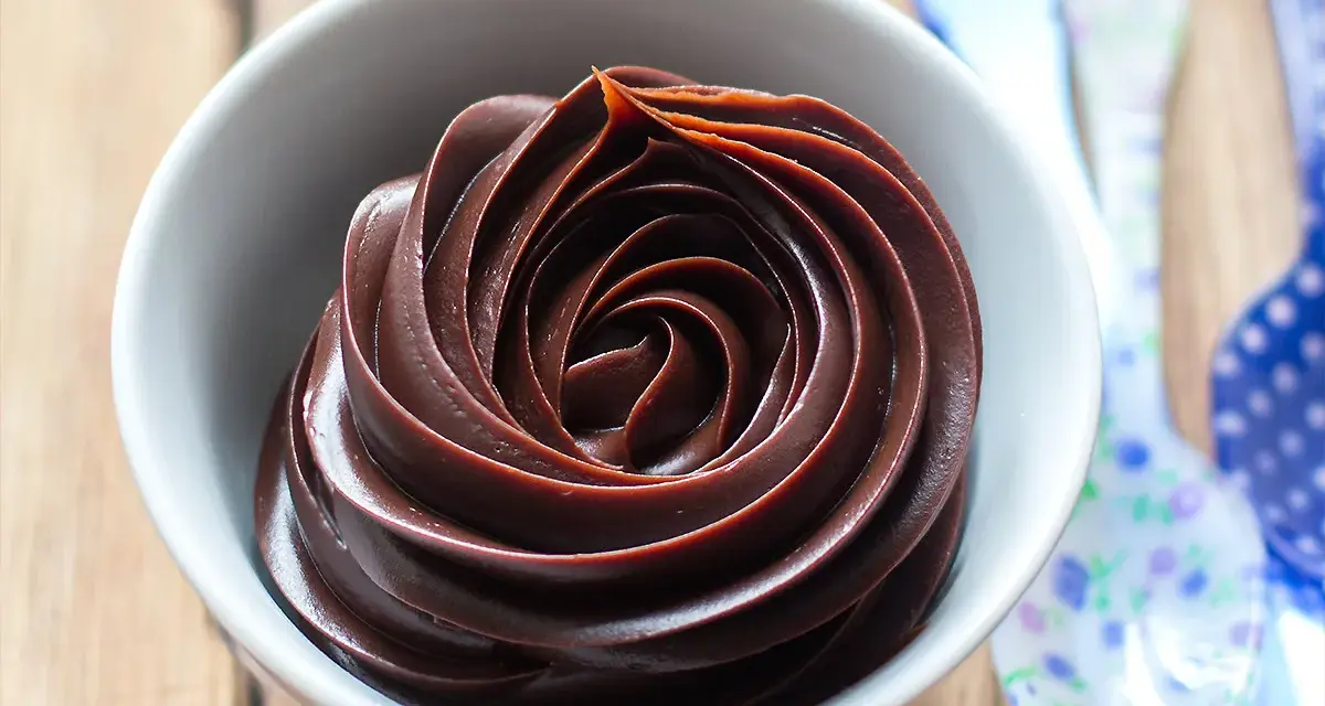 Una ciotola bianca piena di lucida ganache al cioccolato, disposta a spirale.