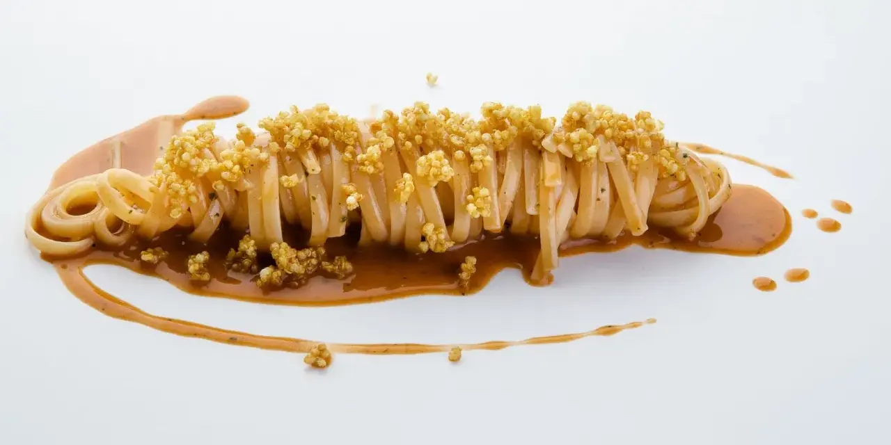 Pasta con carciofi Cannavacciuolo, un piatto elegante con pasta lunga, salsa cremosa e croccanti germogli di quinoa.