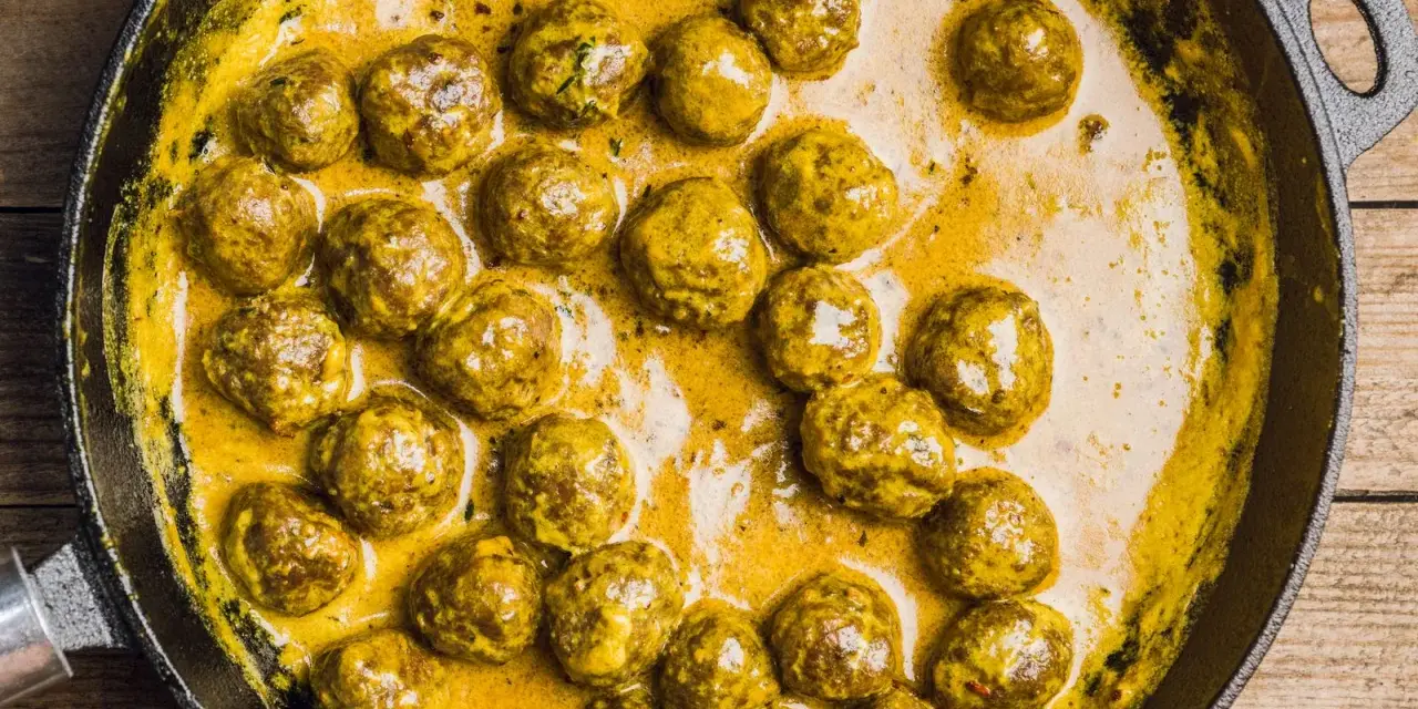 Polpette in bianco cremose in padella, dorate e succulente, immerse in una salsa gialla e invitante.