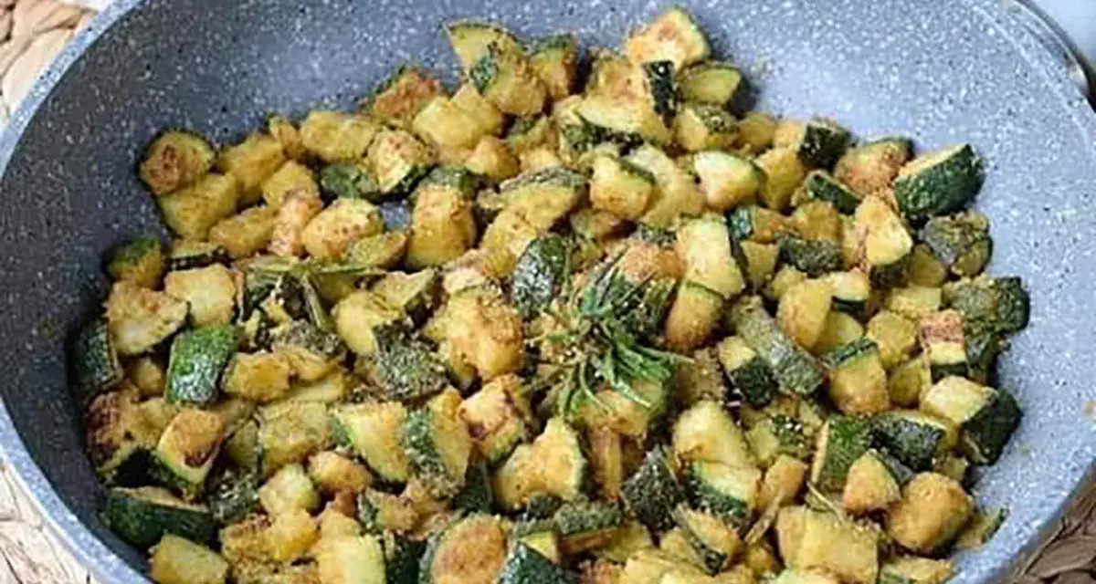 Zucchine gratinate in padella, dorate e saporite, con un rametto di rosmarino fresco.