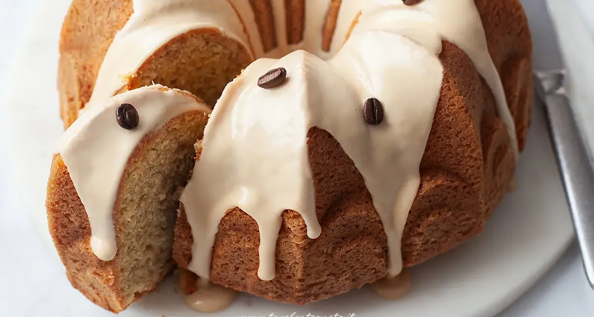 Deliziosa torta al caffè con glassa chiara e chicchi di caffè come decorazione. Una fetta è stata tagliata, mostrando la morbidezza dell'interno.