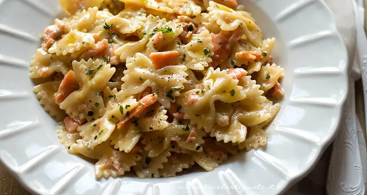Farfalle cremose con pezzetti di salmone e prezzemolo tritato, un piatto invitante di pasta al salmone.