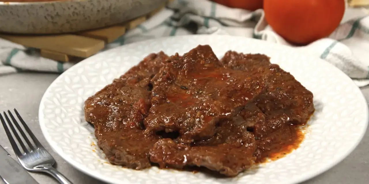 Piatto di carne alla pizzaiola morbida, succulenta e profumata, con pomodoro e spezie.