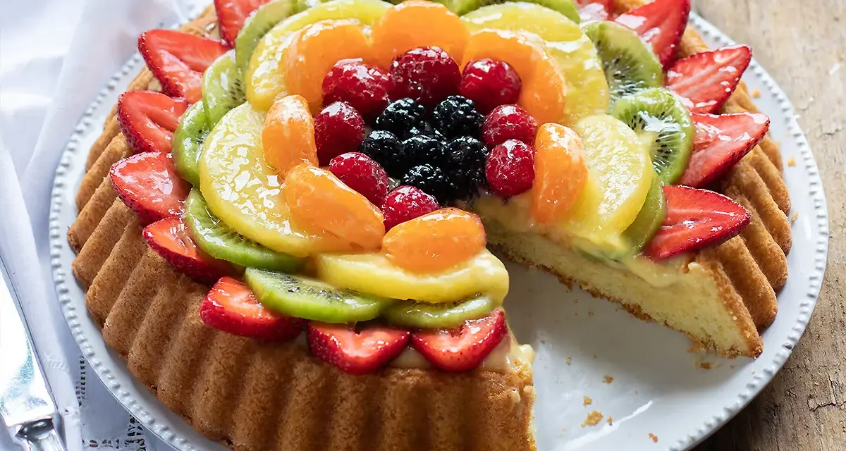 Una deliziosa crostata morbida alla frutta, con fragole, kiwi, mandarini e frutti di bosco, su una base soffice e crema pasticcera.