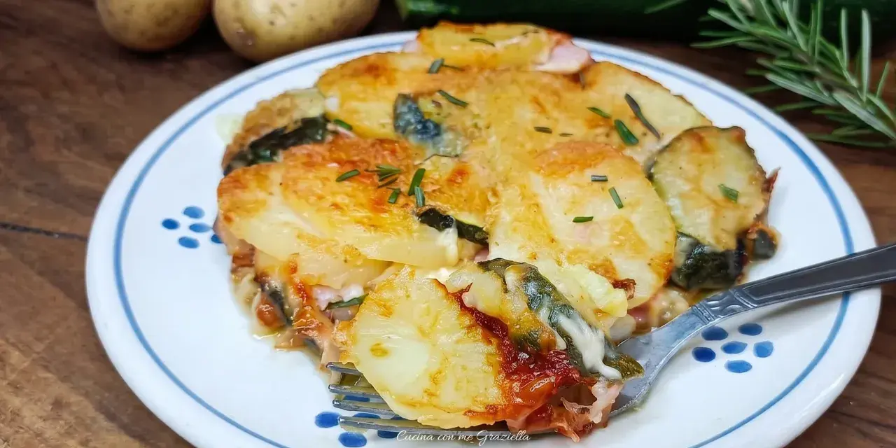 Piatto invitante di patate e zucchine al forno, dorate e filanti, con rosmarino fresco. Un contorno perfetto per ogni pasto.