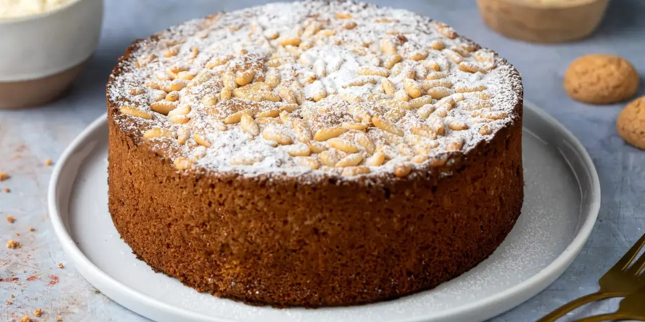 Torta soffice con farina di mandorle, ricoperta di pinoli e zucchero a velo. Perfetta per una pausa golosa.