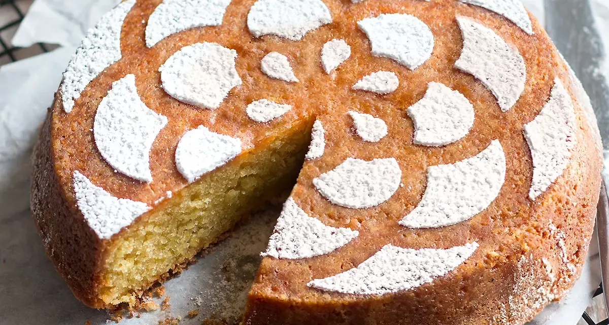 Torta soffice caprese al limone, decorata con zucchero a velo a forma di fiore.