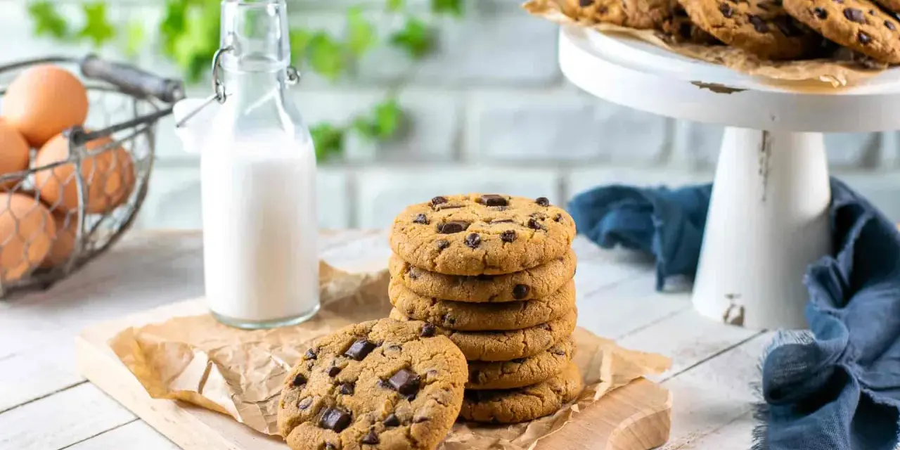 Una pila di deliziosi biscotti con gocce di cioccolato, pronti per essere gustati con un bicchiere di latte.