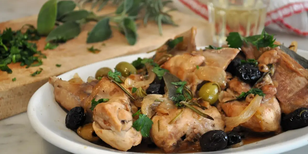 Un saporito coniglio alla cacciatora in bianco, con olive verdi e nere, cipolle e rosmarino, pronto per essere gustato.