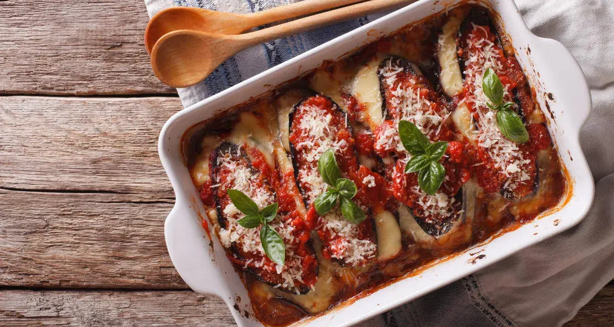 Parmigiana di melanzane appena sfornata, con melanzane, pomodoro, mozzarella filante e basilico fresco.