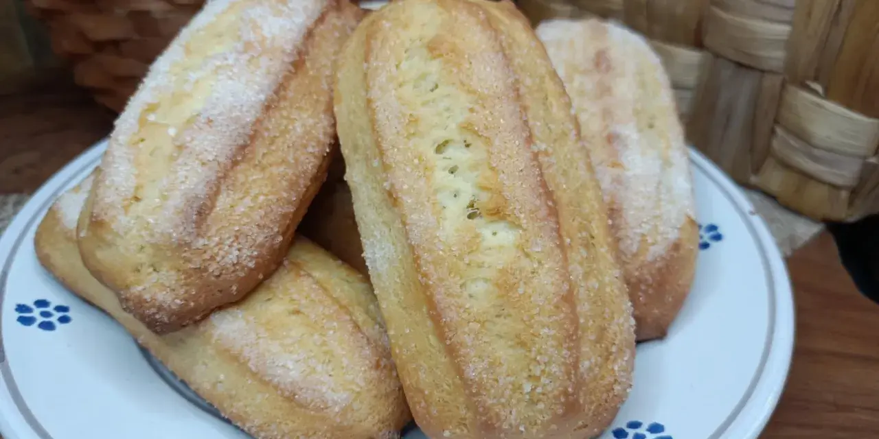Biscotti da inzuppo dorati e zuccherati, perfetti per la colazione o la merenda. Sullo sfondo, un cestino di uova e un altro intrecciato.