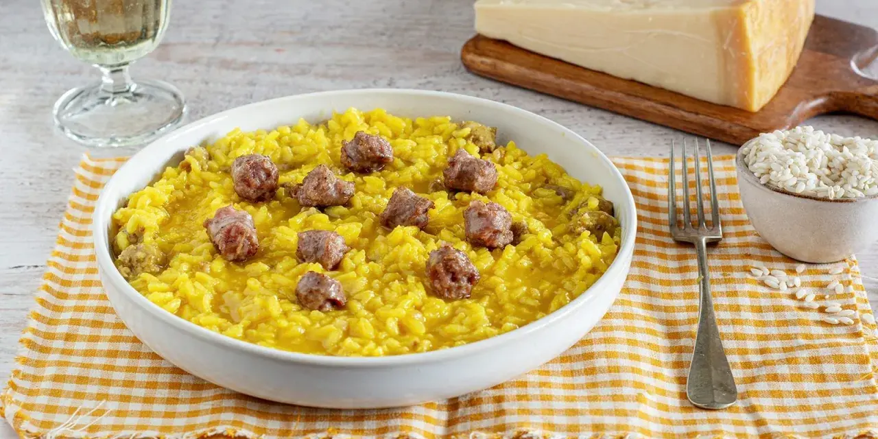 Un invitante risotto alla monzese, giallo intenso e arricchito da pezzetti di salsiccia, pronto per essere gustato.