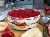 Un invitante tiramisù alle fragole in una ciotola di vetro, con savoiardi, crema e fragole fresche.