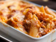 Penne al forno con sugo di pomodoro e mozzarella filante, un classico della pasta alla sorrentina.