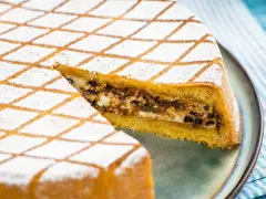 Una fetta di cassata al forno, con la sua copertura a rombi di zucchero a velo, rivela un ripieno goloso di ricotta e cioccolato.
