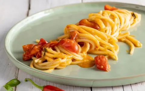 Spaghetti allo scarpariello fumanti, con pomodorini succosi e un tocco piccante, pronti per essere gustati.