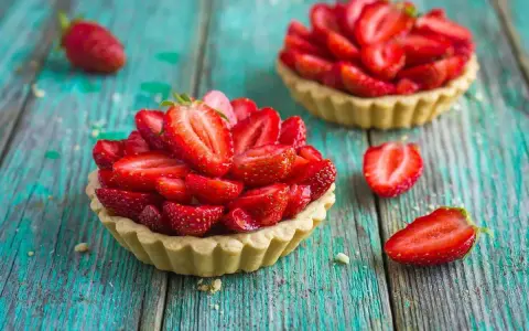 Deliziosi dolci con fragole fresche, disposti su un tavolo di legno turchese.