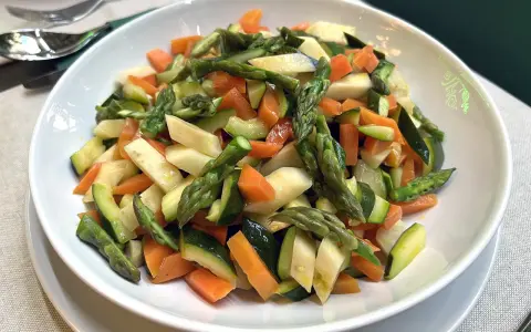 Un piatto invitante di verdure in padella: carote, zucchine e asparagi tagliati a pezzetti, cotti al punto giusto.