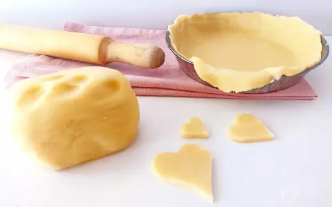 Impasto per pasta frolla senza glutine pronto per essere trasformato in dolci cuori e una crostata.