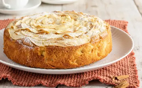 Deliziosa torta di mele senza burro, con mele a rosa sulla superficie e una spolverata di zucchero a velo. Perfetta per la colazione o la merenda.