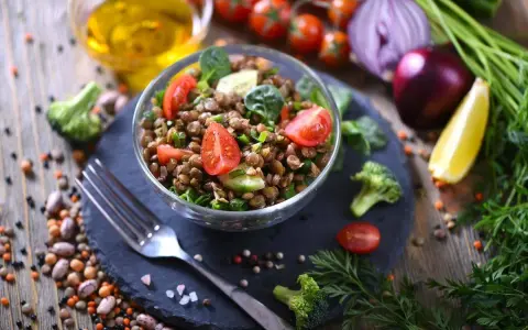 Un'insalata di lenticchie fresca e colorata, con pomodorini, cetrioli e spinacini, pronta per essere gustata.