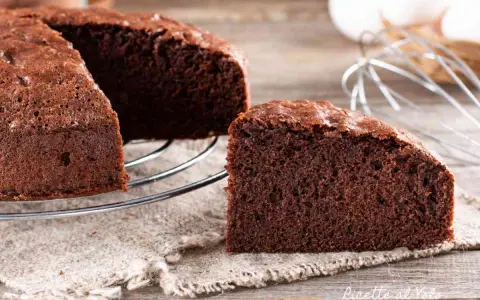 Una fetta di torta al cioccolato soffice e invitante, appena sfornata, su un tavolo di legno.