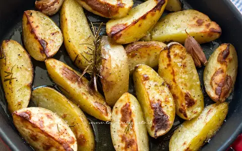 Patate al forno dorate e croccanti, condite con rosmarino e aglio, pronte per essere gustate.