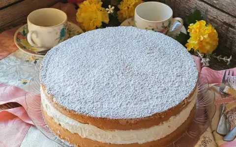 Torta Kinder Paradiso soffice e cremosa, cosparsa di zucchero a velo, pronta per essere gustata con un tè.