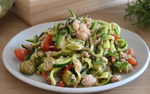 Deliziosa insalata di zucchine a spirale con tonno, pomodorini e olive verdi. Un piatto fresco e leggero.