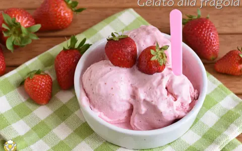 Una ciotola di cremoso gelato alla fragola, guarnito con fragole fresche, su una tovaglietta a quadri verdi.