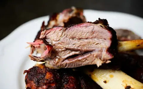 Succulento stinco di maiale affumicato, cotto lentamente fino a diventare tenerissimo. La carne rosa e succosa si stacca dall'osso.