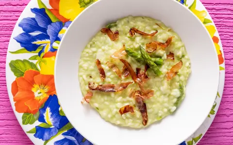 Un cremoso risotto asparagi e speck, guarnito con punte di asparagi freschi e croccanti listarelle di speck.