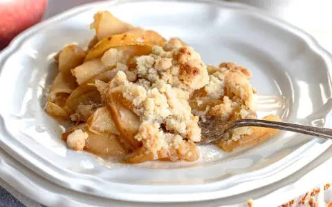 Un delizioso crumble di mele appena sfornato, con mele caramellate e una croccante copertura dorata.