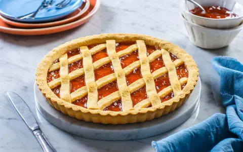 Una deliziosa crostata di marmellata con una griglia dorata di pasta frolla, pronta per essere gustata.