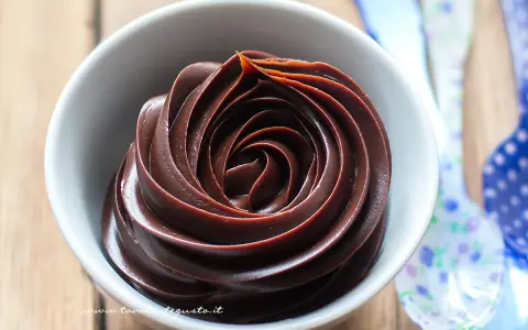 Una ciotola bianca piena di lucida ganache al cioccolato, disposta a spirale.