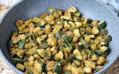 Zucchine gratinate in padella, dorate e saporite, con un rametto di rosmarino fresco.