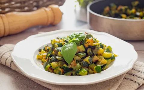 Zucchine in padella, un contorno saporito e colorato, guarnito con basilico fresco.