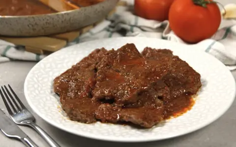Piatto di carne alla pizzaiola morbida, succulenta e profumata, con pomodoro e spezie.