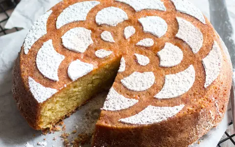 Torta soffice caprese al limone, decorata con zucchero a velo a forma di fiore.