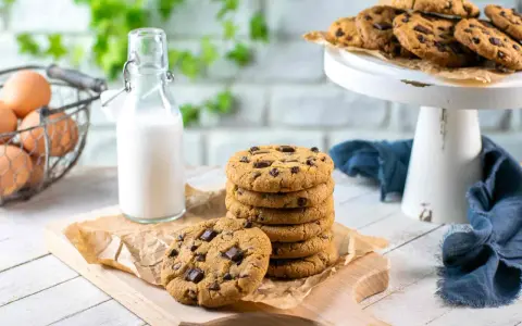 Una pila di deliziosi biscotti con gocce di cioccolato, pronti per essere gustati con un bicchiere di latte.