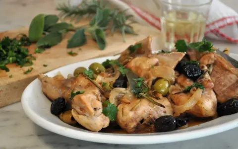 Un saporito coniglio alla cacciatora in bianco, con olive verdi e nere, cipolle e rosmarino, pronto per essere gustato.