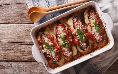 Parmigiana di melanzane appena sfornata, con melanzane, pomodoro, mozzarella filante e basilico fresco.