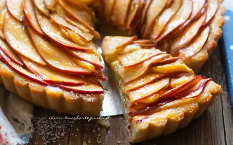 Una fetta di crostata di mele lucida e dorata, con le mele disposte a spirale su una base friabile.