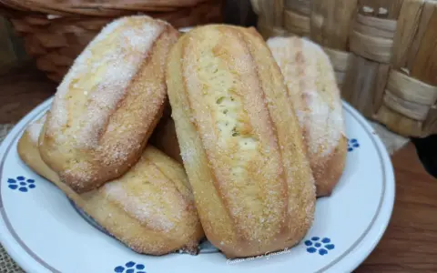 Biscotti da inzuppo dorati e zuccherati, perfetti per la colazione o la merenda. Sullo sfondo, un cestino di uova e un altro intrecciato.