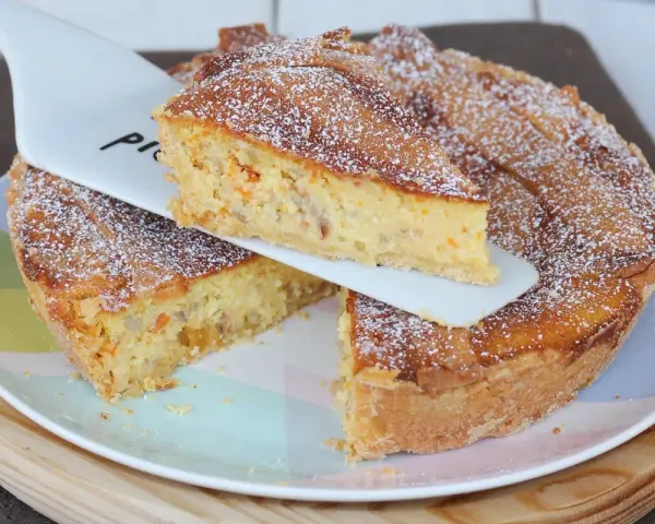 Una fetta di pastiera napoletana con pasta frolla, ricca di grano, ricotta e canditi, cosparsa di zucchero a velo.