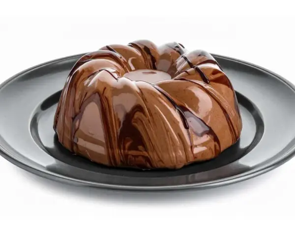 Bavarese al cioccolato con glassatura lucida e striature di cioccolato fondente su piatto scuro.