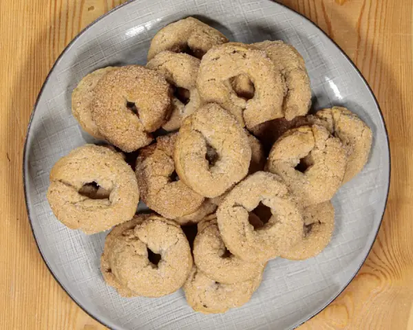 Piatto di ciambelline al vino, dolcetti friabili e dorati, perfetti per accompagnare un caffè o un tè.