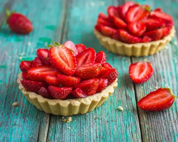 Deliziosi dolci con fragole fresche, disposti su un tavolo di legno turchese.