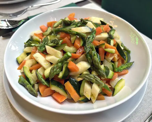 Un piatto invitante di verdure in padella: carote, zucchine e asparagi tagliati a pezzetti, cotti al punto giusto.