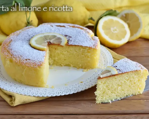 Una soffice torta ricotta e limone, spolverata di zucchero a velo e decorata con fettine di limone. Perfetta per una pausa golosa.